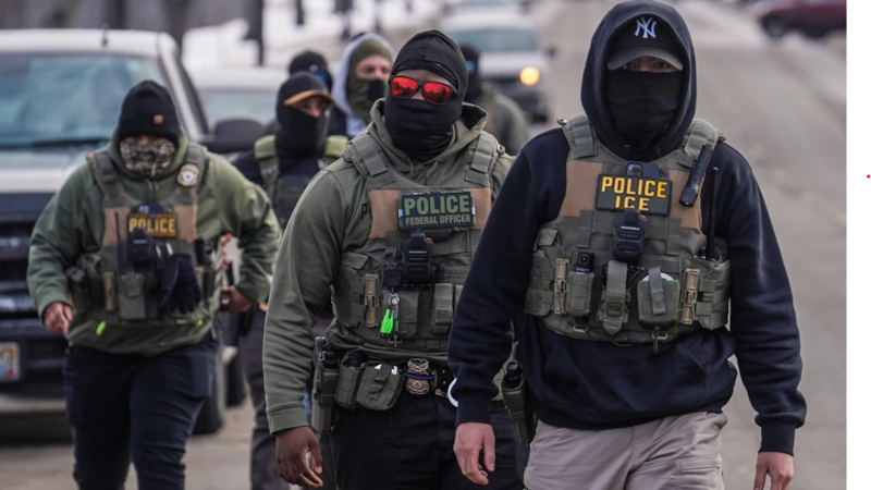 Federal agents walk down a street while conducting immigration enforcement operations in...