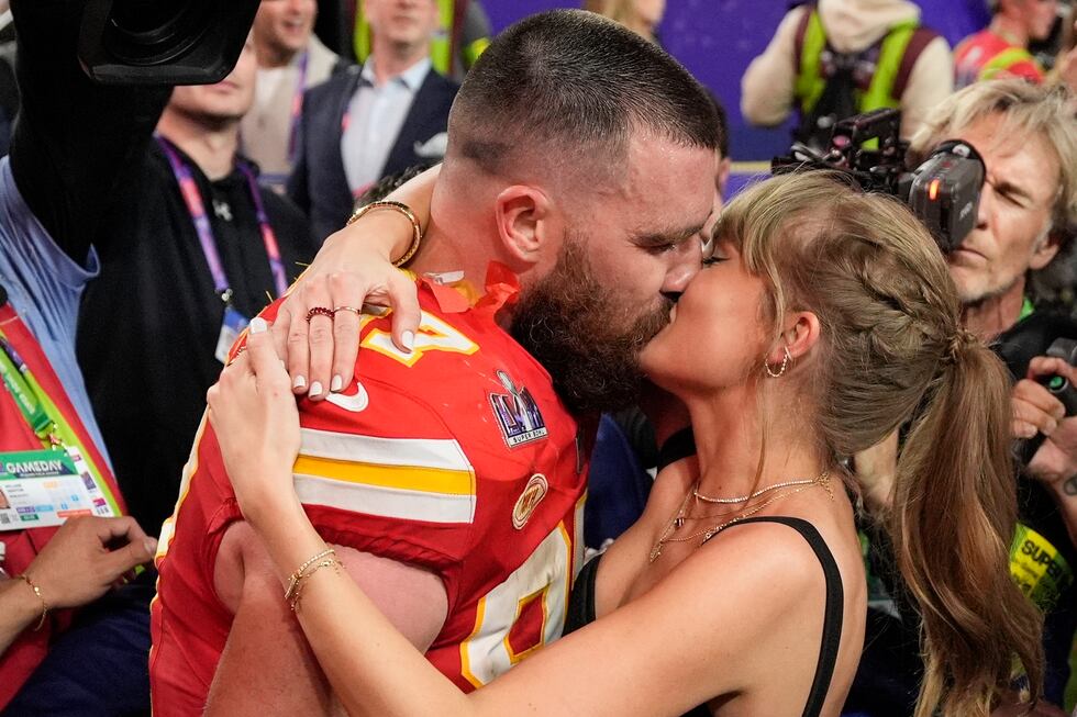 ARCHIVO - El ala cerrada de los Kansas City Chiefs, Travis Kelce (87), besa a Taylor Swift...